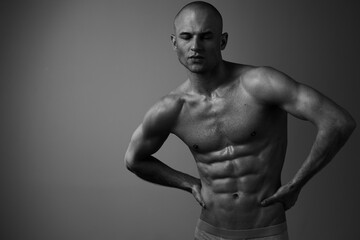 Fototapeta premium Black and white image of a muscular man posing confidently, showcasing his toned physique and athleticism, exuding strength and determination.