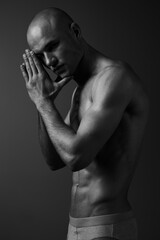 Fototapeta premium Black and white portrait of a contemplative man, showcasing strong emotion and artistry, emphasizing the contrast of light and shadow in striking details.