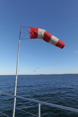 Flag in the blue sky. Red and white wind flag, wind direction and speed