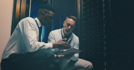 Engineer, men and teamwork with tablet, server room and planning for software upgrade or discussion. Data center, people and review of information technology, IT specialist and network engineering