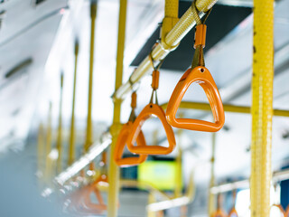 Passenger handholds and grab bars inside public transportation bus or train - safety support handles for commuters in urban transit vehicle.