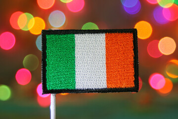Irish flag embroidery patch with colorful rainbow bokeh lights background, symbolizing holiday celebration, national day, independence, and festive spirit.