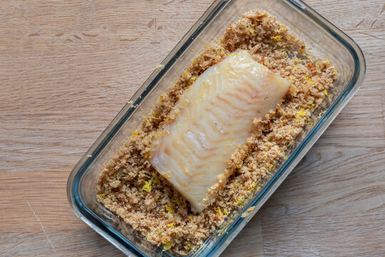 Coating haddock fillet with breadcrumbs containing oregano and lemon zest background backdrop.