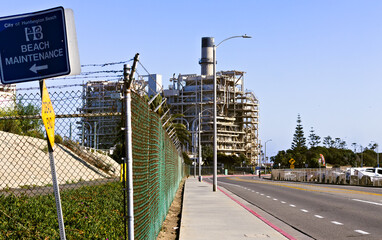 Industrial power plant near Huntington Beach with road, fence, and maintenance signs under a clear...