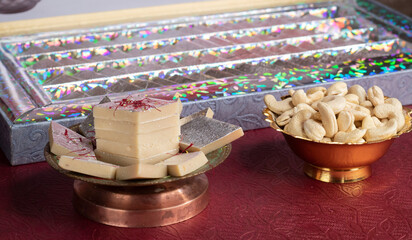 Kaju Katli is a Diamond shape Indian sweet made using cashew sugar and mava served in a plate over moody background