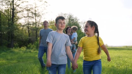 Children holding hands walk through green meadow while boy and girl beam with mother following smiling family and child enjoying outdoor play in grass sunlight happy connection nature joy healthy
