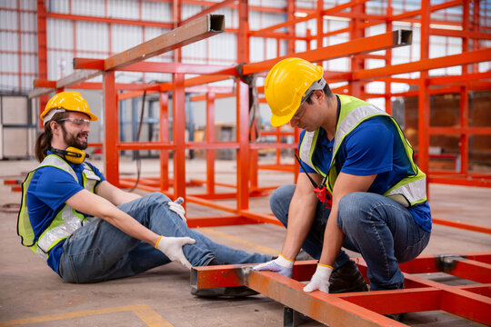 Factory worker injured during accident being assisted by colleague, representing workplace safety, industrial injury, emergency response, teamwork in hazardous environment.