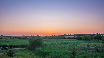 Sunset over a lush green field, creating a beautiful evening view of the countryside.