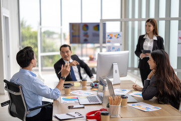 Female executive presents to her team in a contemporary office setting, where an asian businesswoman guides colleagues through strategic planning and business discussion, representing corporate leader