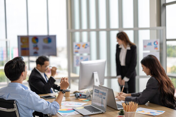 Female executive presents to her team in a contemporary office setting, where an asian businesswoman guides colleagues through strategic planning and business discussion, representing corporate leader