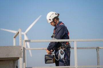Engineer working in front of wind turbines for checking wind turbines of the field during beautiful sunset. Alternative energy concept.