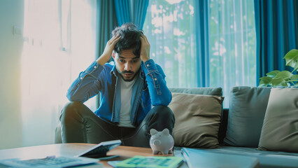 Stressed man calculating home finances with piggy bank