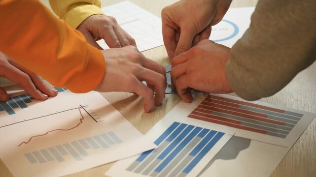 Placing puzzle piece over chart and graph while team collaboration on strategy planning and analysis with finance data spread across table with bar and line chart and report for teamwork and decision