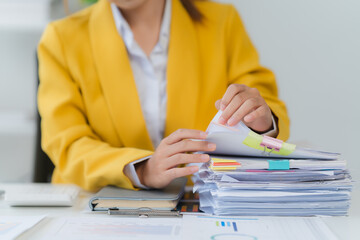 Focused Analysis: A person carefully reviews a stack of important documents at the office desk....