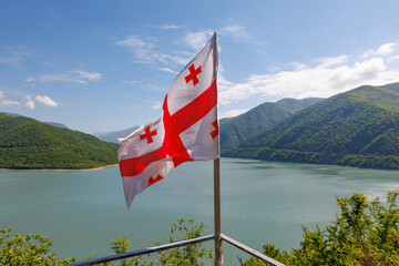 Scenic view of Georgian flag waving in front of the Zhinvali Reservoir in the Caucasus Mountains,...