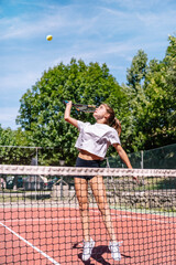Female athlete serving during a tennis match on a sunny day, demonstrating impressive skill and athleticism on the clay court