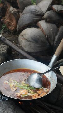 Cooking mie nyemek in a rice field with traditional outdoor style and rustic countryside atmosphere. Indonesian noodle dish prepared in a natural rural environment, showcasing local culinary culture, 