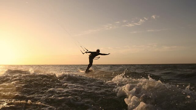 Dynamic kitesurfer riding powerful wave in slow motion during golden hour sunset showing extreme water sport adrenaline strength energy movement and breathtaking athletic outdoor lifestyle - Powered by Adobe