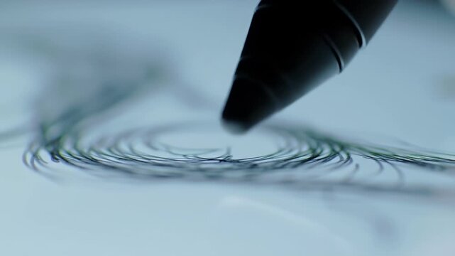 Close Up of Black Stylus Drawing Spirals on a Digital Tablet Screen
