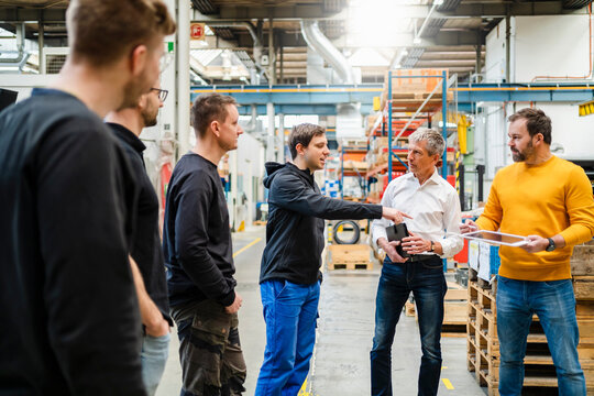 Employee asking manager in meeting at factory