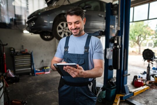Car mechanic using a digital tablet in a auto repair shop