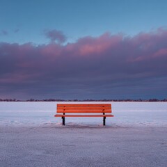 Empty orange bench on snowy expanse at dawn