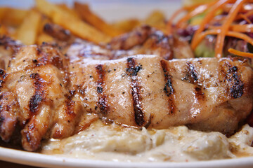 Grilled chicken served with fries and salad on a plate