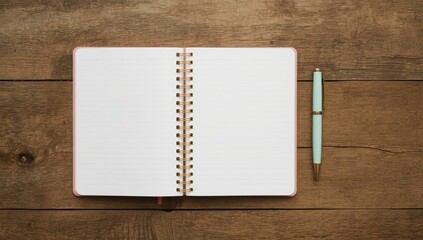 A light pink spiral-bound notebook rests open on a wooden surface, beside a light teal pen, showcasing a blank page ready for writing.