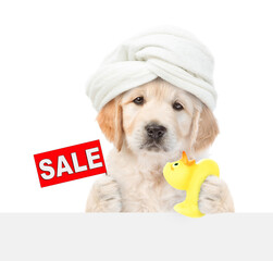 Cute Golden Retriever puppy with towel on it head holds rubber duck and shows signboard with labeled "sale" above blank white banner. isolated on white background