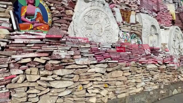 Colorful Tibetan mani stone wall with intricate Buddhist carvings, sacred scriptures, and vibrant deity paintings in Yushu, Qinghai (Amdo), China.