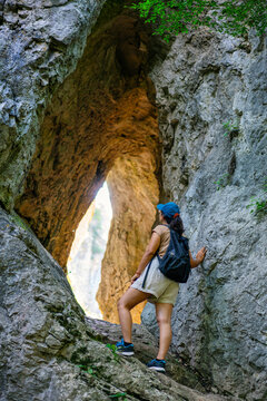 Woman hiking in natural rock arch at Vratna caves, Serbia