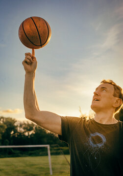 A man spins a basketball on his index finger