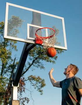 A man catches a basketball from below the hoop