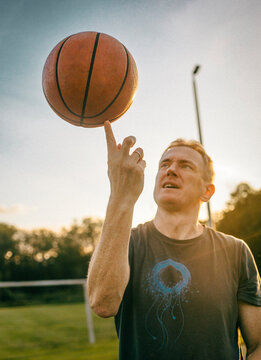 A man spins a basketball on his index finger