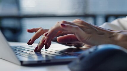Close-up shot of elegantly manicured hands swiftly typing on a sleek, silver laptop keyboard. The setting is a modern, minimalist corporate office bathed in soft.