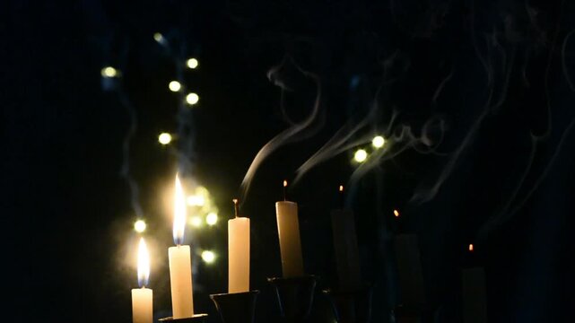 Hanukkah celebration candles glowing on a black background with warm festive light. Traditional Jewish holiday decoration featuring menorah candle flames, spiritual atmosphere, cultural symbolism, and