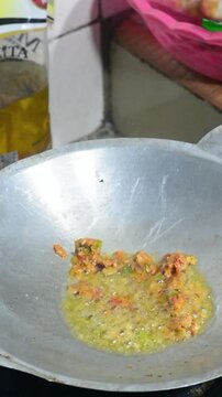 Homemade seblak cooking process with various toppings in a home kitchen. Popular Indonesian spicy street food prepared with authentic ingredients, flavorful seasonings, noodles, crackers, and assorted