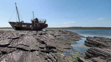 old wrecked sunken ship on the rocky shore of the Arctic Ocean is the
