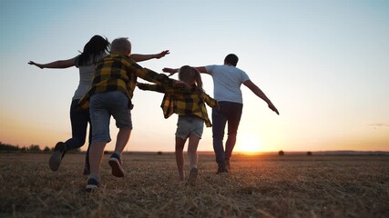 Running with family toward sunset child and sibling run and play in open field summer light joy and carefree energy family running and play in warm dusk sunset family bond playful run under warm sky