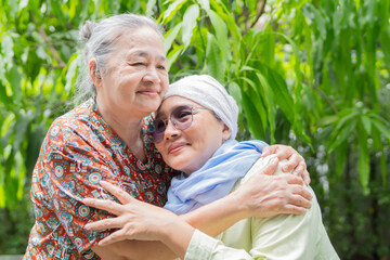 Happy, sweet and sick mature female person embracing her adult daughter with a smile at outdoor