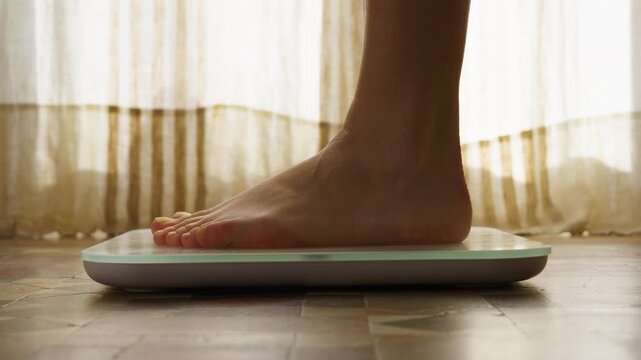 Feet standing on scales, checking BMI weight loss. Measuring body fat overweight barefoot.