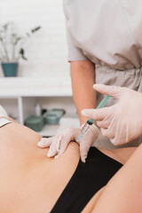 Injections of lipolytic into the abdomen for weight loss and muscle definition in the office of a cosmetologist, close-up. The doctor in sterile gloves inject lipolytic into abdomen subcutaneously