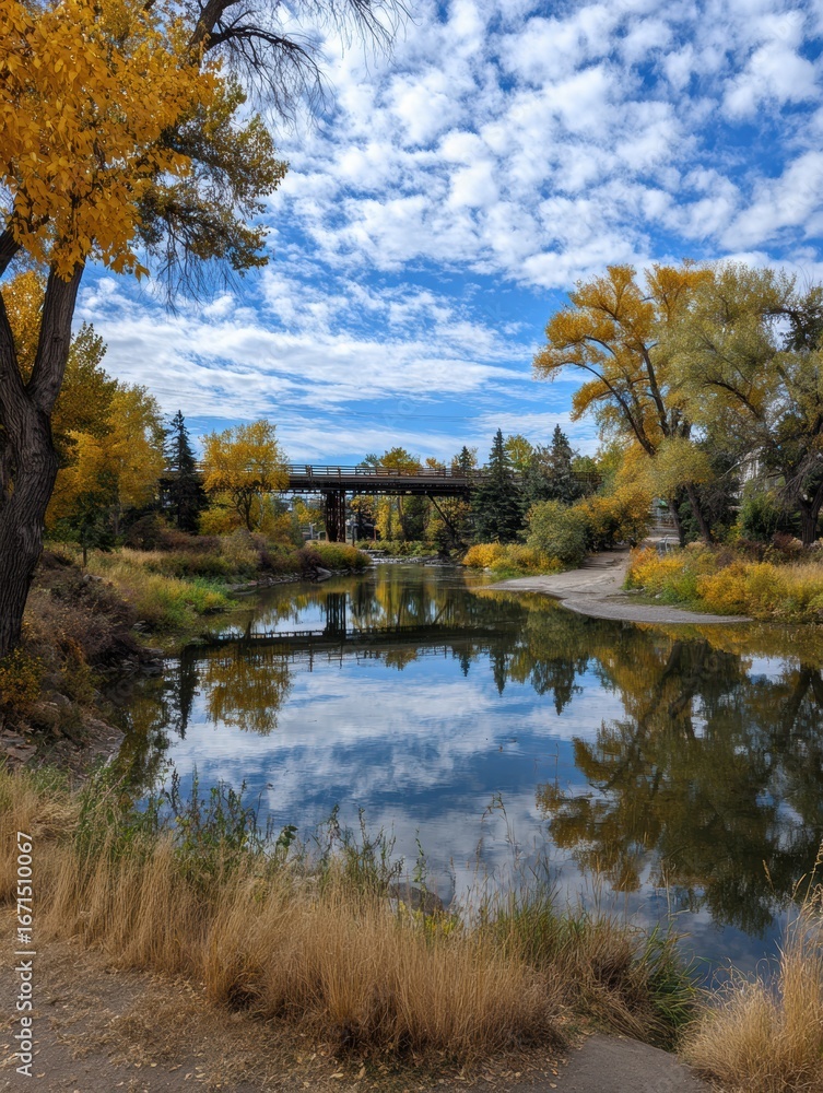Poster reflection of autumn foliage and a bridge over a calm river in a serene park setting