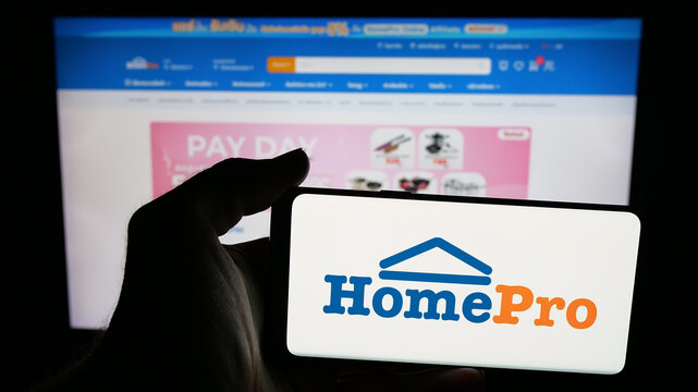 Stuttgart, Germany - 08-25-2025: Person holding mobile phone with logo of Thain home improvement retail company HomePro on screen in front of web page. Focus on phone display.