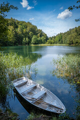 Rowboat on shore of Žalieji Ežerai Green Lakes Vilnius Lithuania with calm water, green forest and blue summer sky in peaceful Baltic countryside nature © Fineshot