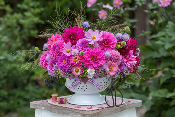 Blumen-Arrangement mit pink Dahlien, Schmuckkörbchen, Ziniien, Scabiosen und Gräsern im vintage Durchschlag	