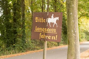 Road sign showing horse rider and asking drivers to slow down in german