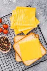 Square  Slices of processed Cheddar cheese in individual plastic packaging. grey background. top view