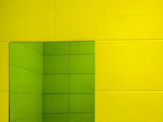 Green rectangular mirror reflecting verdant ceramic tiles against yellow wall, generating geometric abstraction with vibrant architectural visual impact
