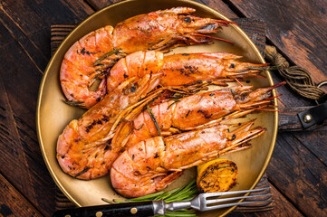 Grilled red Argentine shrimps, Prawns Langostino Austral on a plate with herbs. wooden background. top view